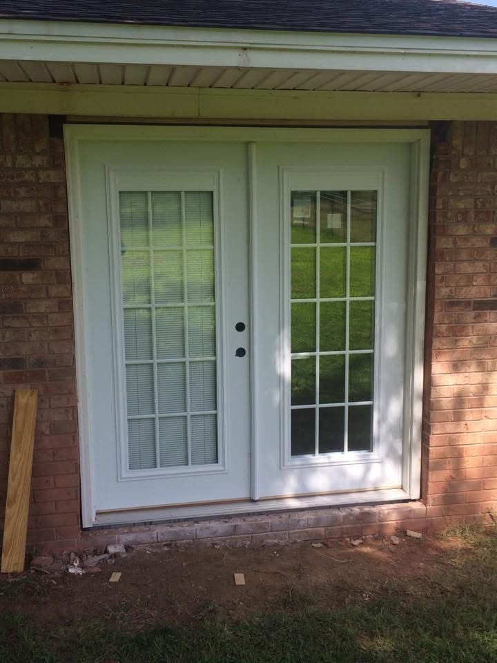 New white French doors installed in a brick wall